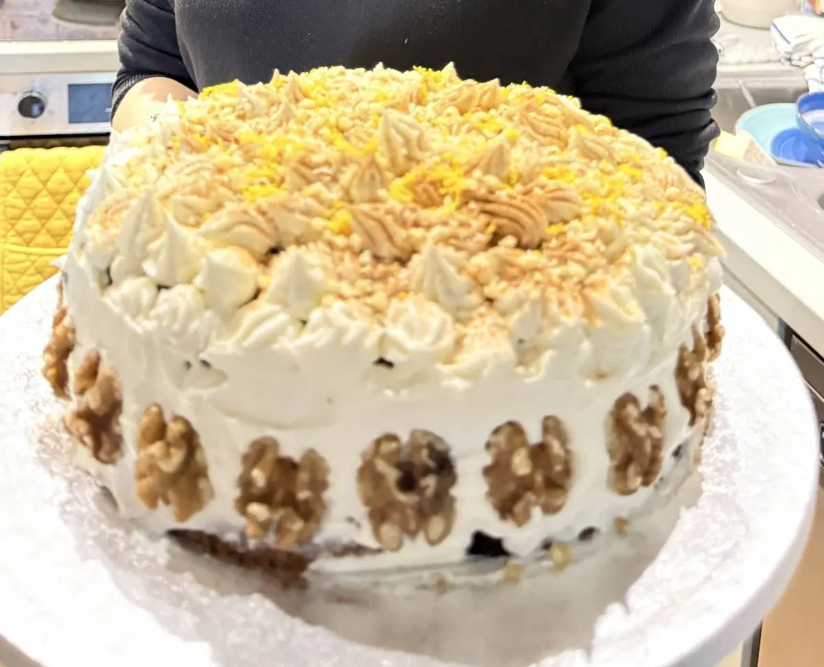 Aggie's carrot and walnut cake, finished with piped cream cheese frosting, orange zest, cinnamon and a ring of walnut halves