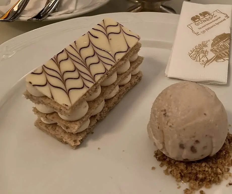 A slice of Eszterházy torte with feathered white icing and walnut layers
